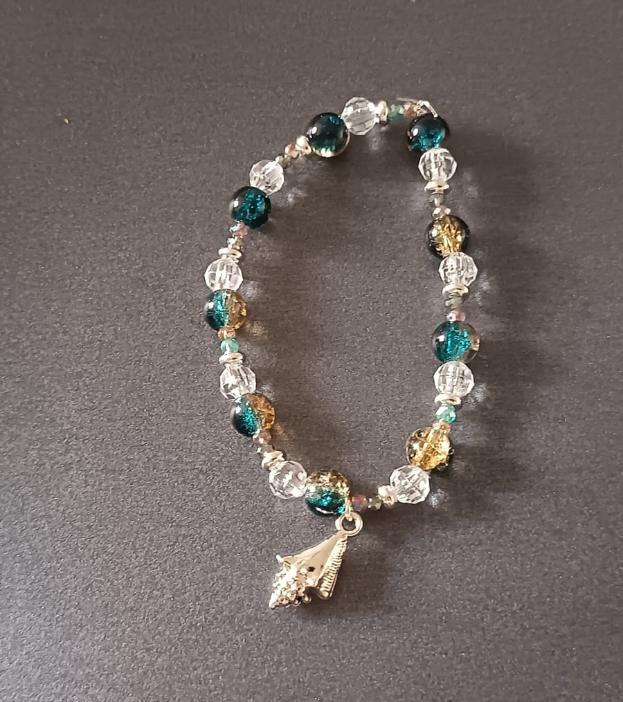 Elasticated bracelet with blue and clear beads and silver shell charm 