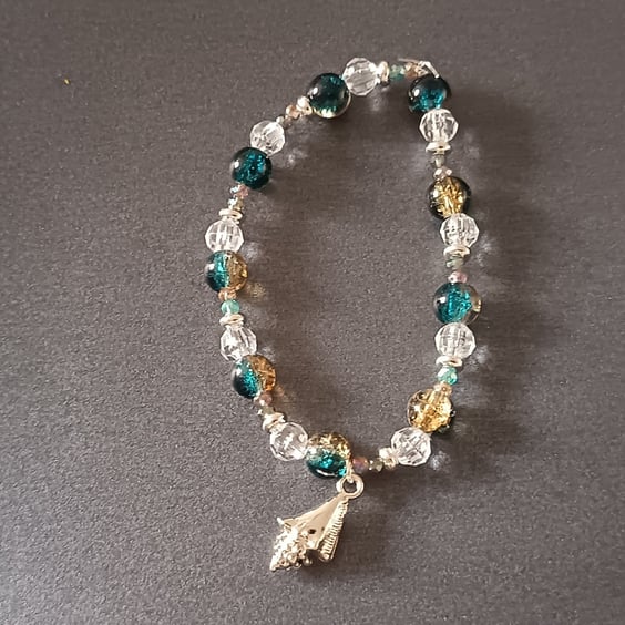 Elasticated bracelet with blue and clear beads and silver shell charm 