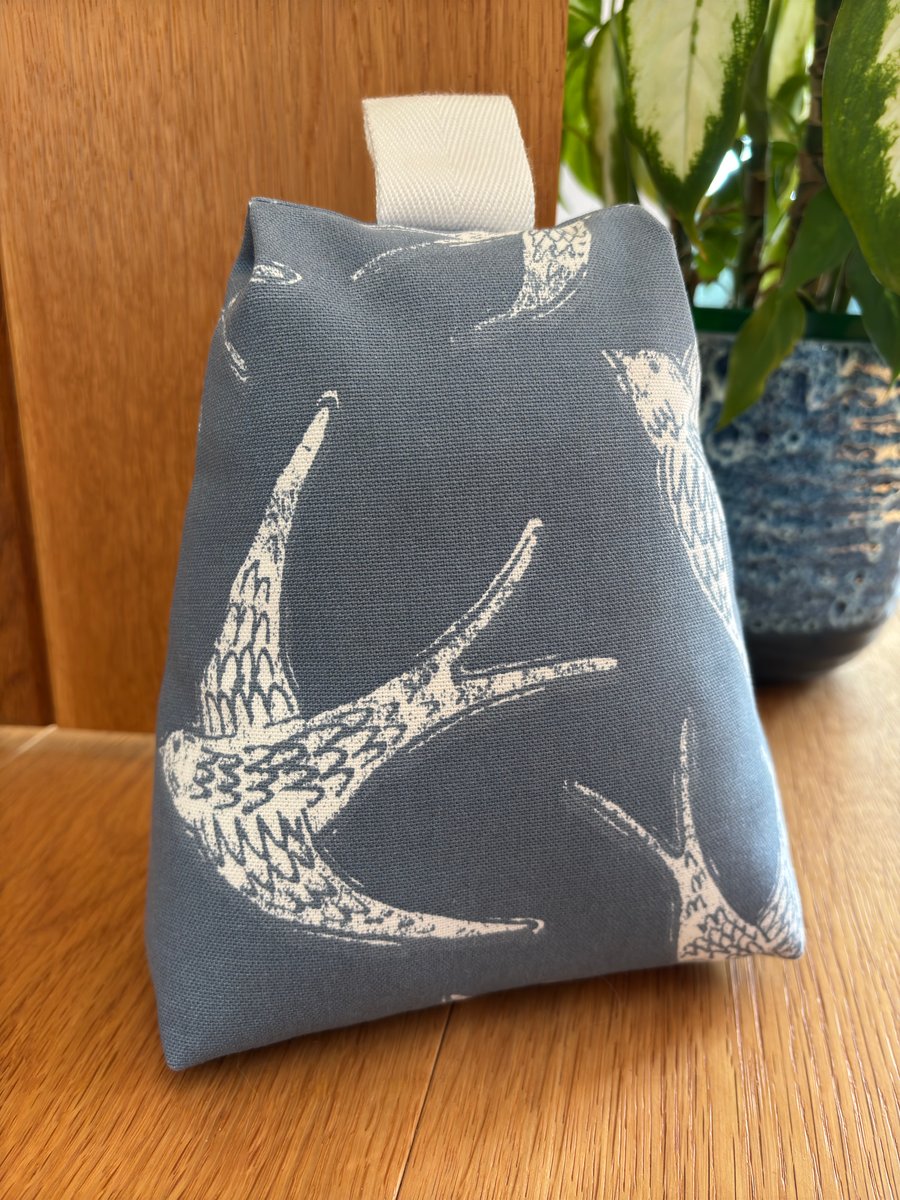Cotton fabric doorstop in navy with white bird print, filled with pebbles.