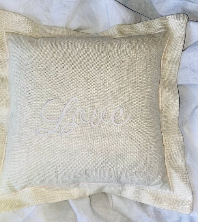The word LOVE embroidered in White on a Cream Linen Keepsake Cushion