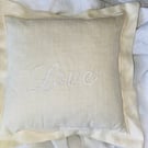 The word LOVE embroidered in White on a Cream Linen Keepsake Cushion