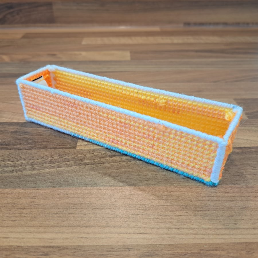 Pencil case - yellow, orange, and pink with blue and white edging, open-top