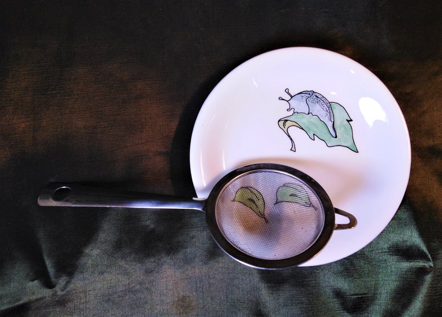 Slug on a leaf tea strainer or ladle rest with a slug on a leaf.