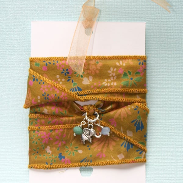 Mustard yellow patterned silk ribbon wrap bracelet with elephant and glass charm