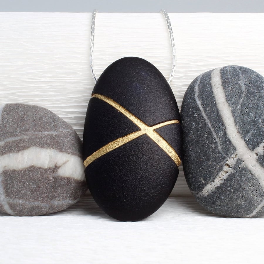 Black Pebble prndant with gilded lines which hangs on a sterling silver chain 