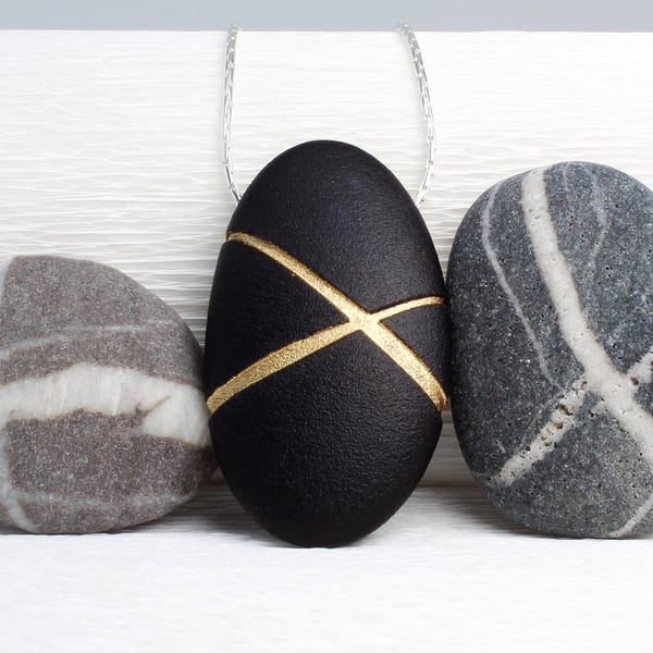 Black Pebble prndant with gilded lines which hangs on a sterling silver chain 