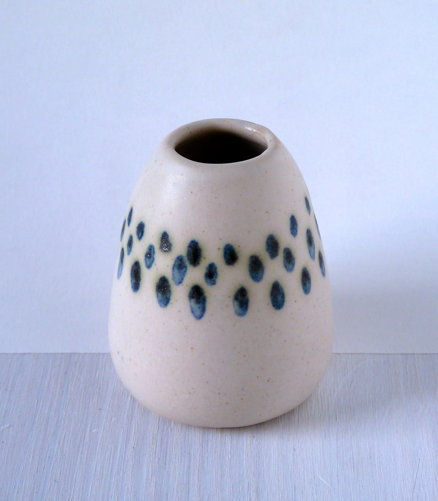 A hand thrown and decorated bud vase .