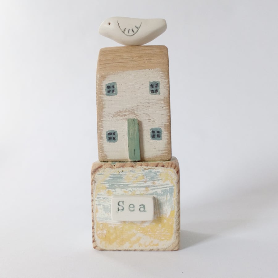 Little wooden seaside house with clay bird on a vintage toy block