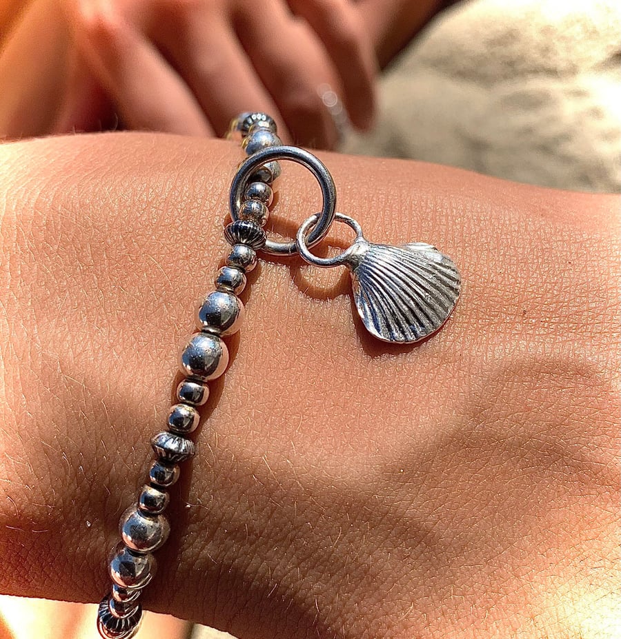 Cast silver shell charm on silver beaded bracelet