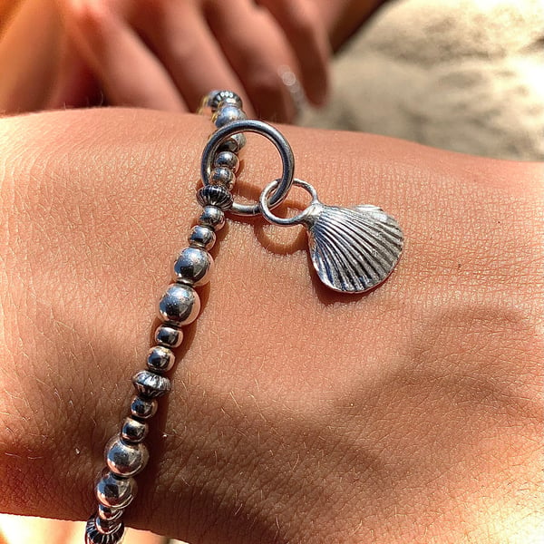 Cast silver shell charm on silver beaded bracelet