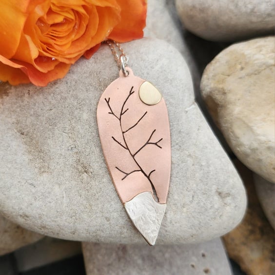 Copper pendant pierced with tree outline and added sterling silver and brass