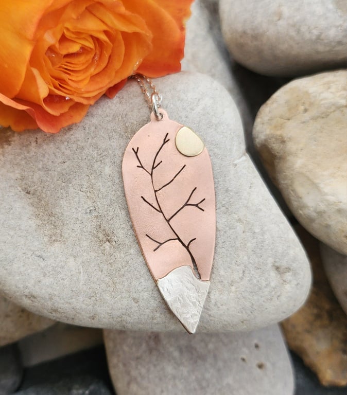 Copper pendant pierced with tree outline and added sterling silver and brass