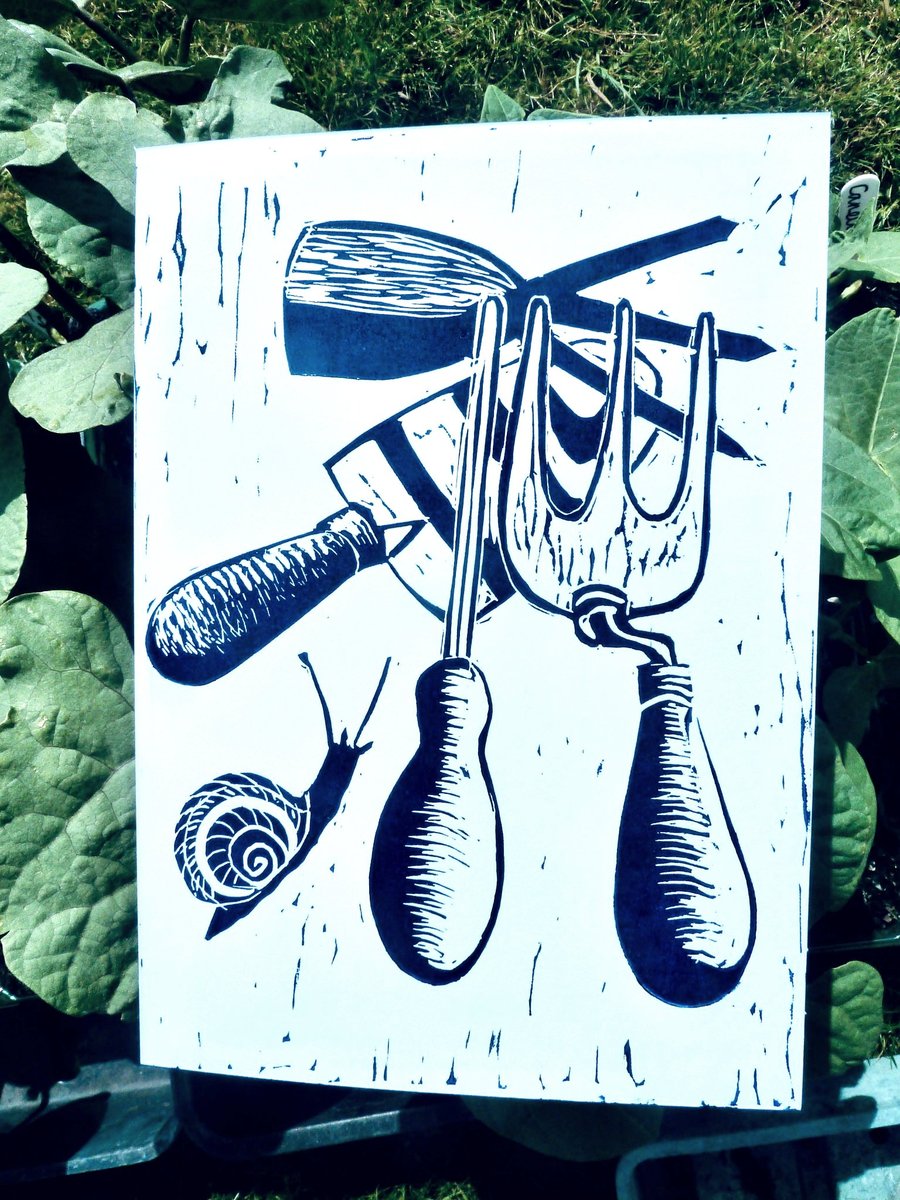 A freshly printed linocut greetings card featuring garden tools