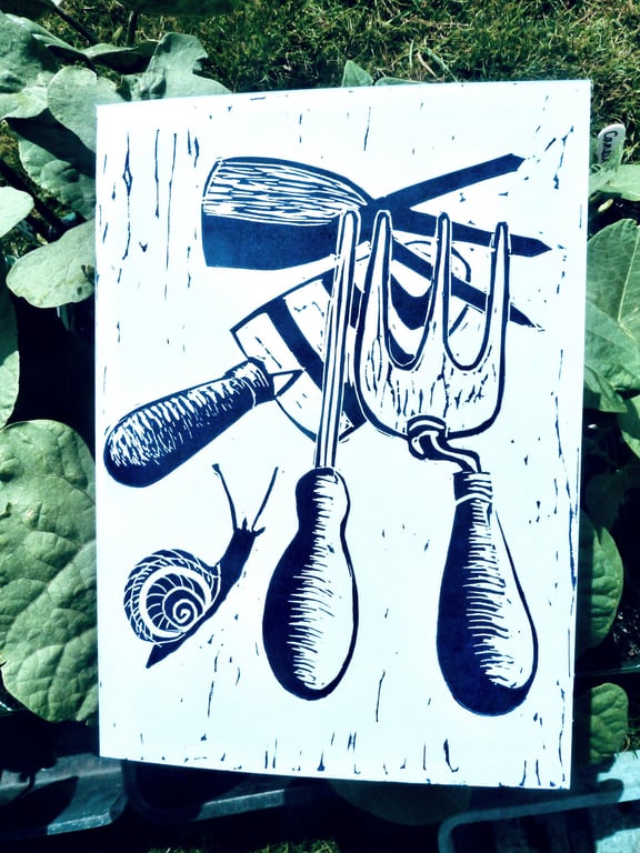 A freshly printed linocut greetings card featuring garden tools