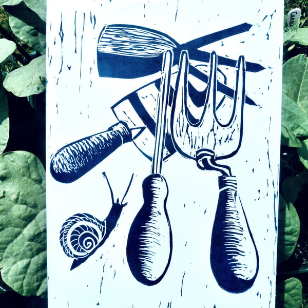 A freshly printed linocut greetings card featuring garden tools