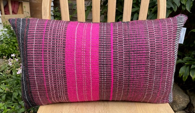 Rose pinks and soft greys in th hand woven cushion made using 100% British wool.