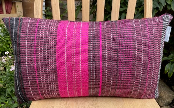 Rose pinks and soft greys in th hand woven cushion made using 100% British wool.