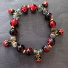 Elasticated red, black and gold beaded ladybird charm bracelet 