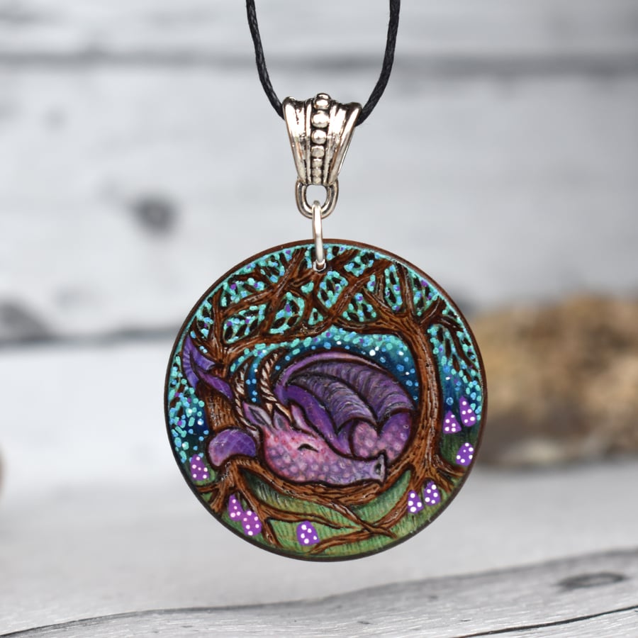 Sleepy dragon with purple toadstools. Pyrography round wood pendant.