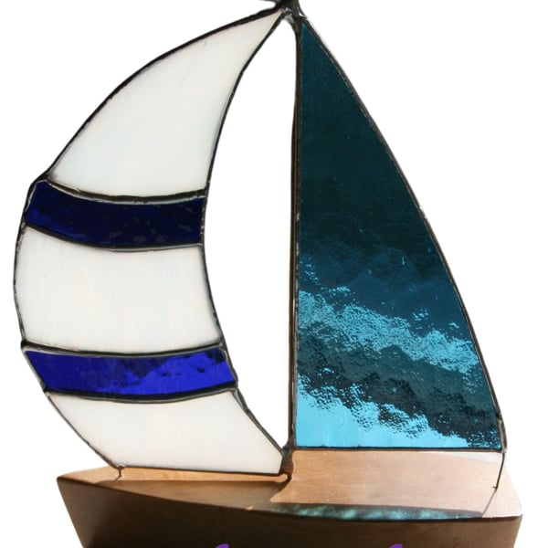 Handmade Yacht with blue stained sails and solid wood shaped boat hull