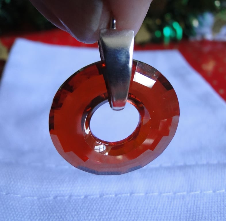 Deep red faceted crystal donut pendant on a silver bail and chain. 