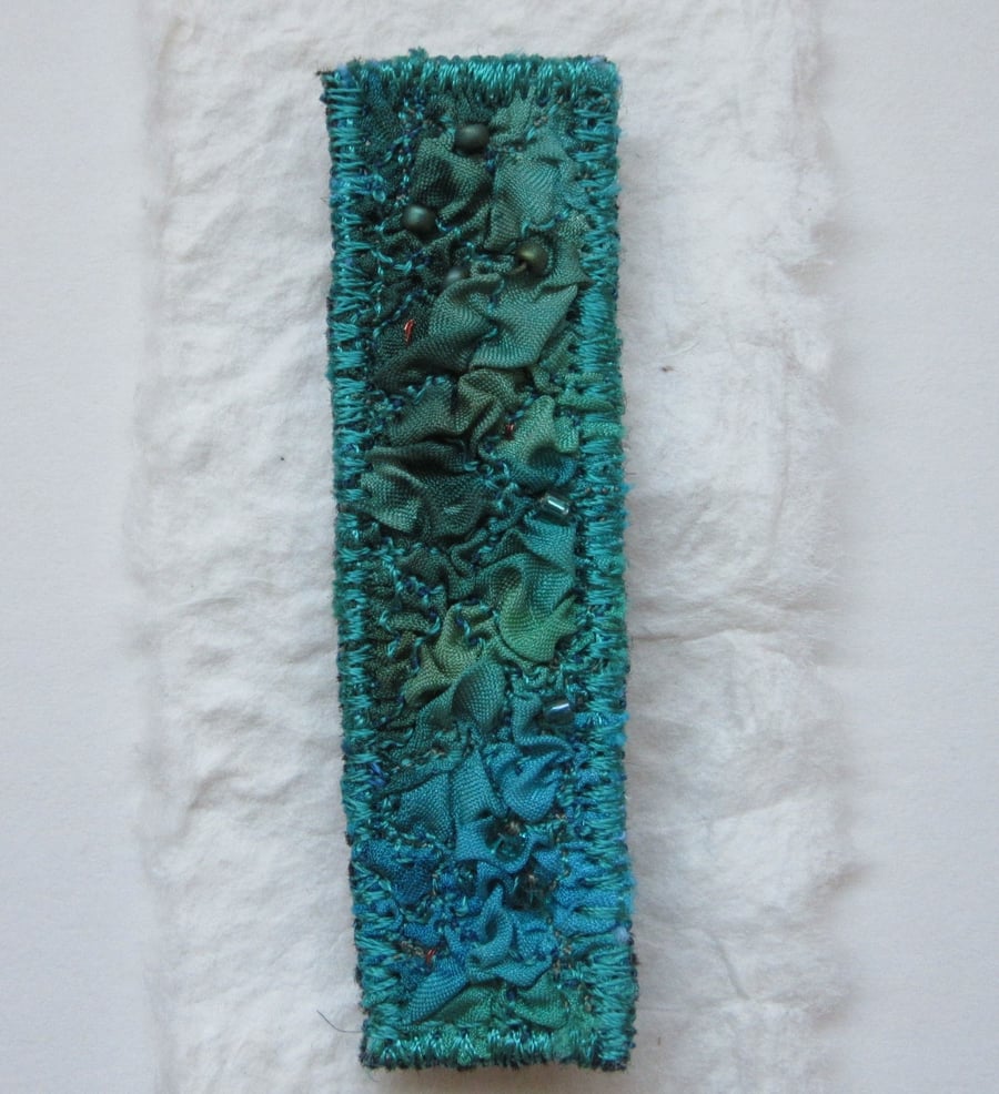 SILK TEXTILE BROOCH with dark jade and turquoise silk machine embroidered fabric