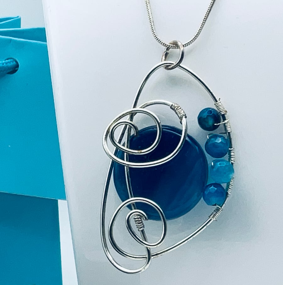 Beautiful blue banded agate pendant held in a silver scroll