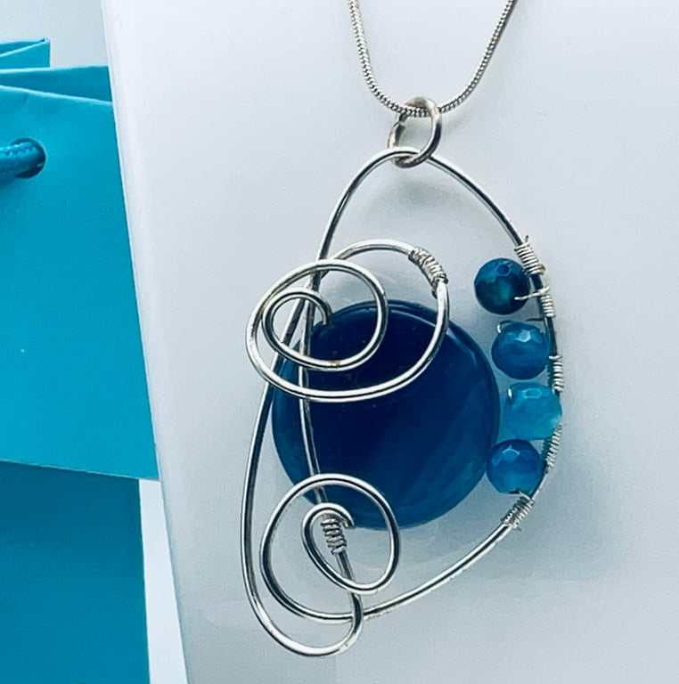 Beautiful blue banded agate pendant held in a silver plated scroll