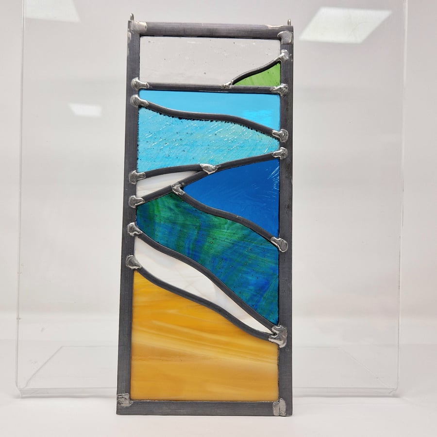 Stained glass beach and wave scene in strong colours, leaded hanging panel.