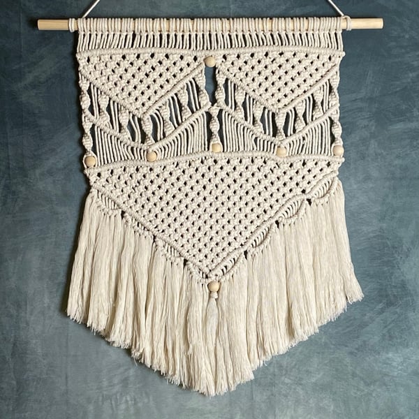 Macrame wall hanging with intricate knot design and wooden beads