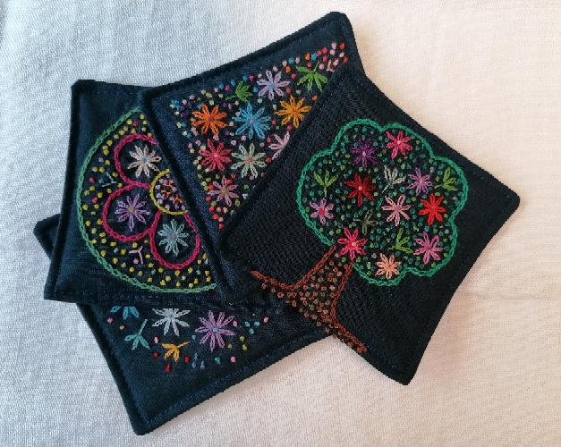 Set of four embroidered fabric coasters. 