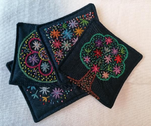Set of four embroidered fabric coasters. 