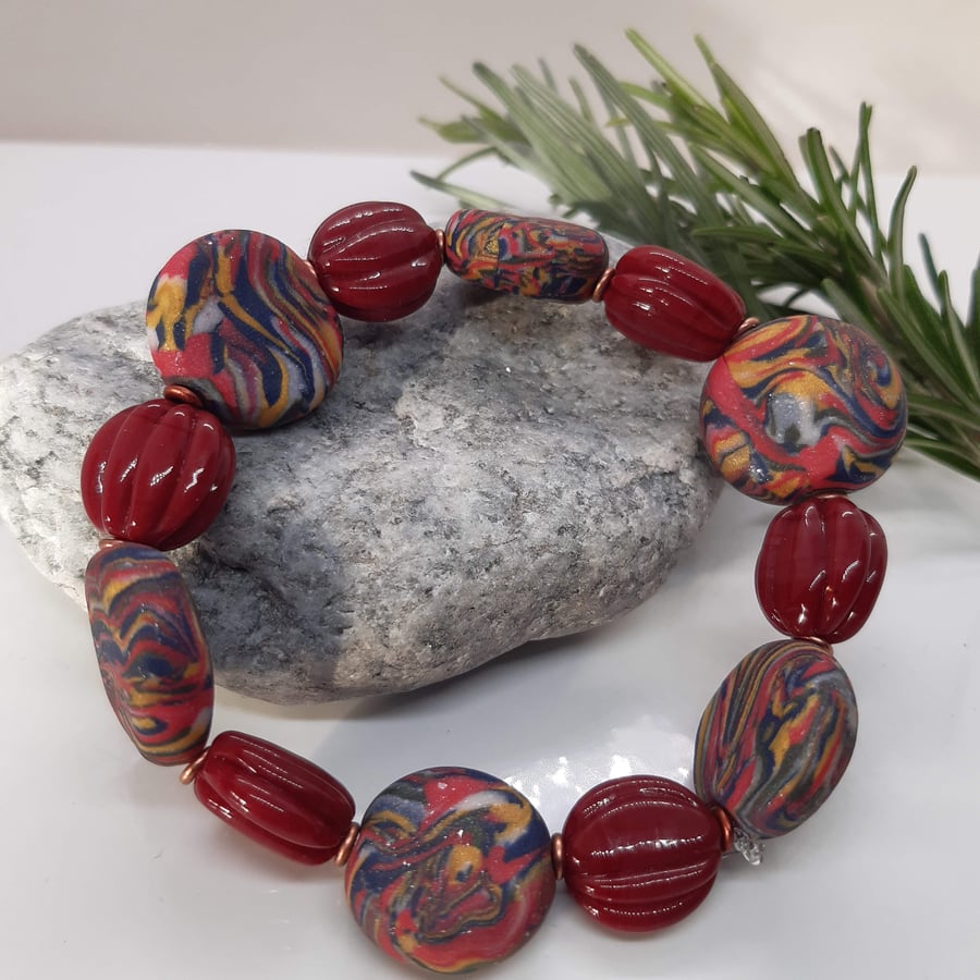 Disc shaped bracelet in red, navy and gold swirl 