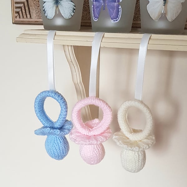 Hand-knitted hanging nursery decorations, pacifiers