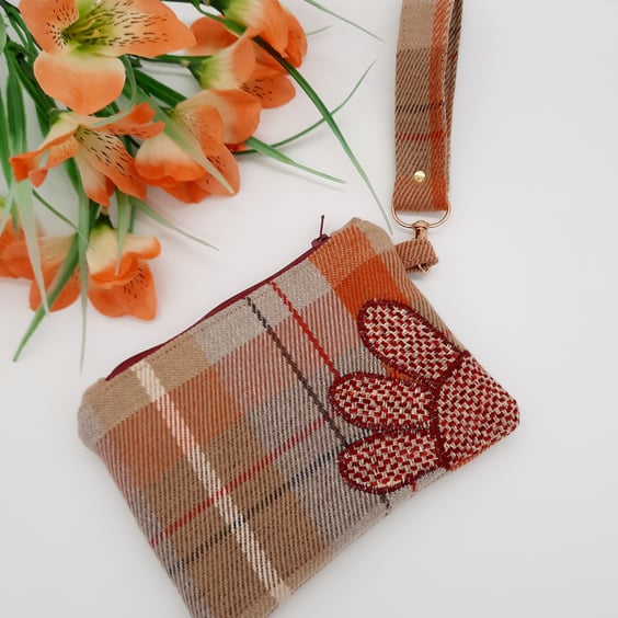 Check clutch bag with clip on handle and flower applique. 