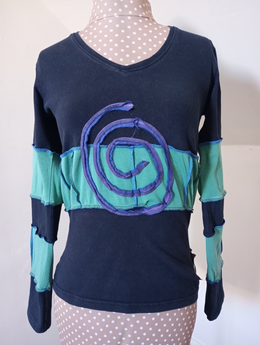 Black and green patchwork top with long sleeves and purple spiral detail 