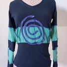 Black and green patchwork top with long sleeves and purple spiral detail 