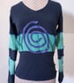 Black and green patchwork top with long sleeves and purple spiral detail 