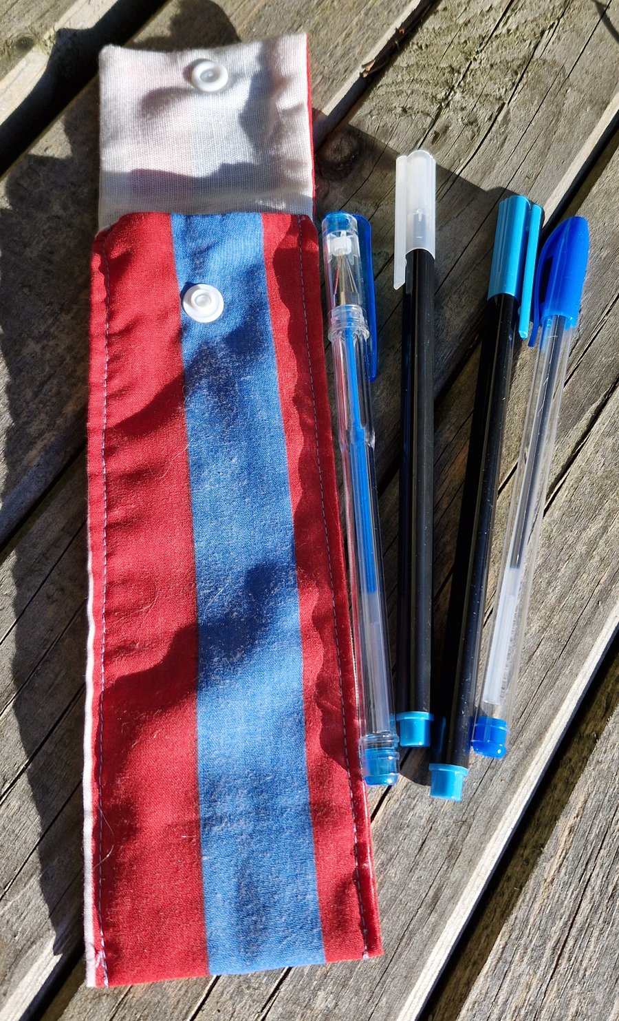 Blue and red striped pen case with 4 blue pens 