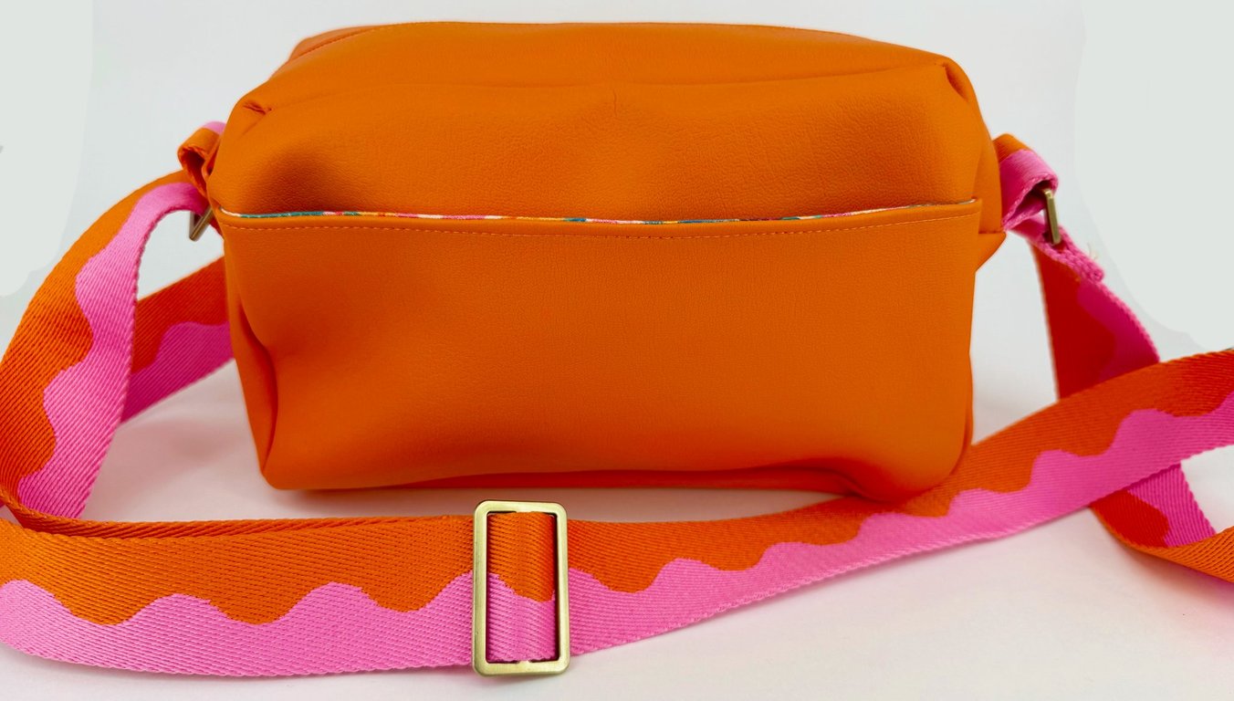 Bright orange faux leather crossbody bag with jazzy lining and roomy interior