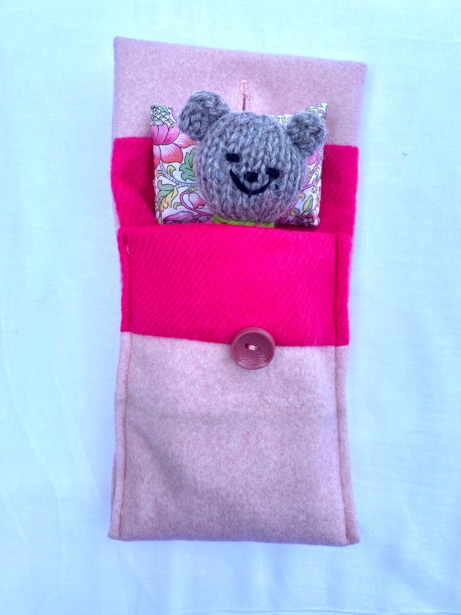 Hand knitted pink baby bear in a bed