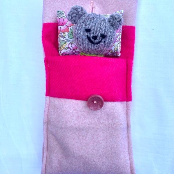 Hand knitted pink baby bear in a bed