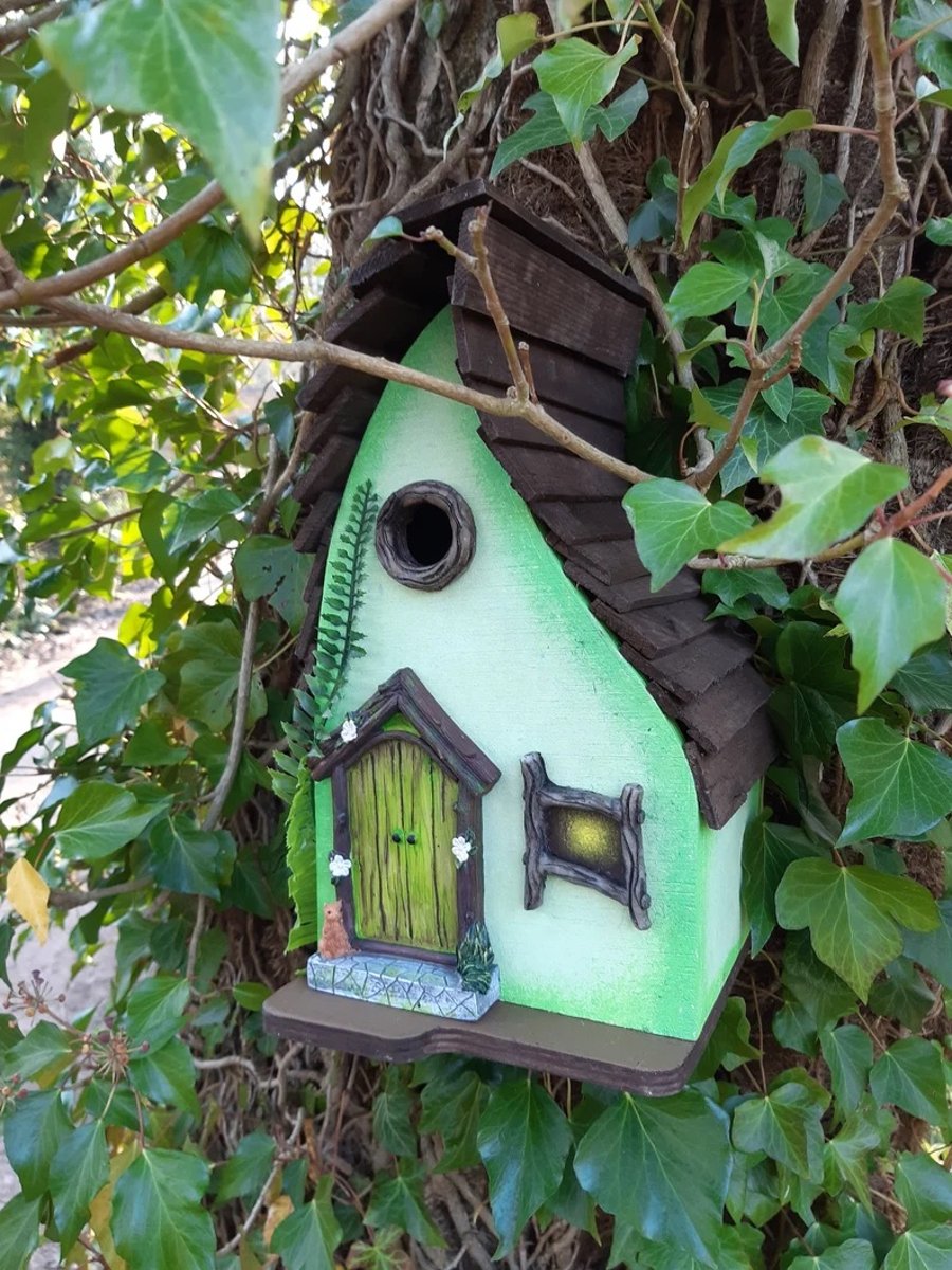 Green wooden bird box made in a fairy house style. Quirky bird house with door. 