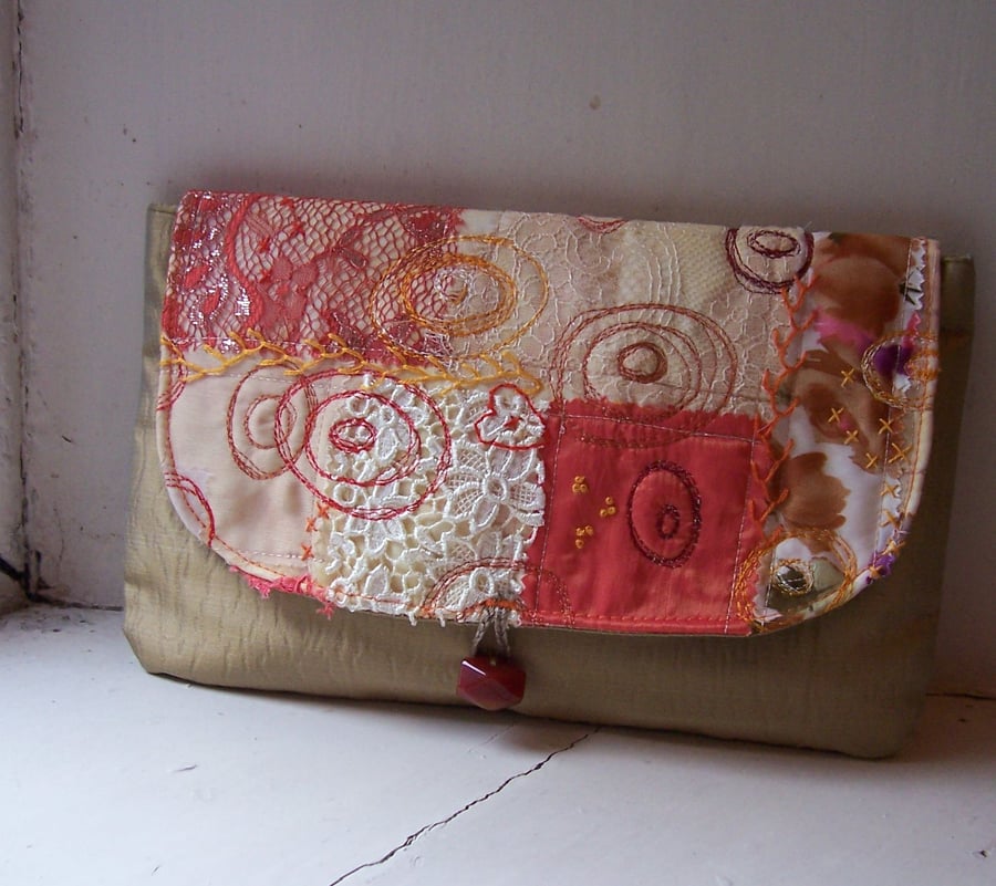 Clutch bag with embroidered and appliqued detail in warm colours and textures