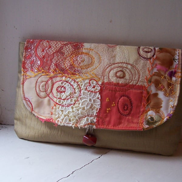 Clutch bag with embroidered and appliqued detail in warm colours and textures