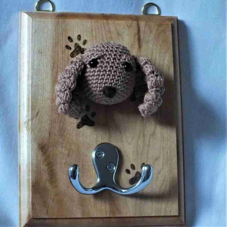 Crocheted spaniel head on wooden board with hooks