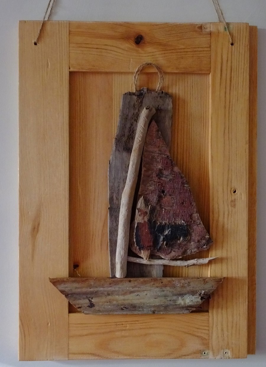Driftwood sailing boat or dinghy mounted in a reclaimed wooden door panel 