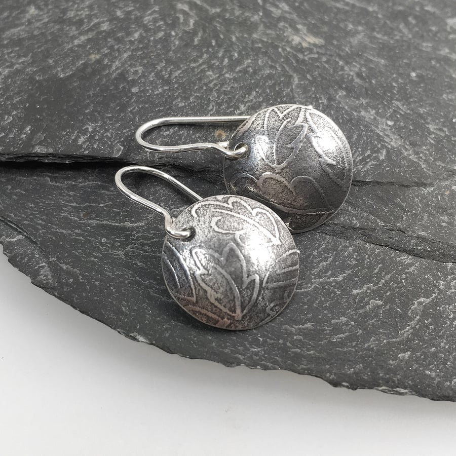 Sterling silver leaf patterned circular earrings.
