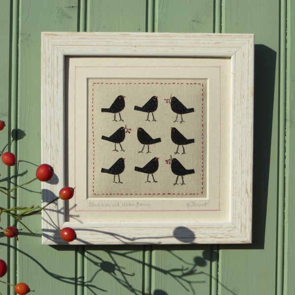 Small framed hand-stitched textile of blackbirds with bright red berries