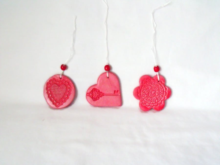 set of three impressed ceramic hanging decorations in red
